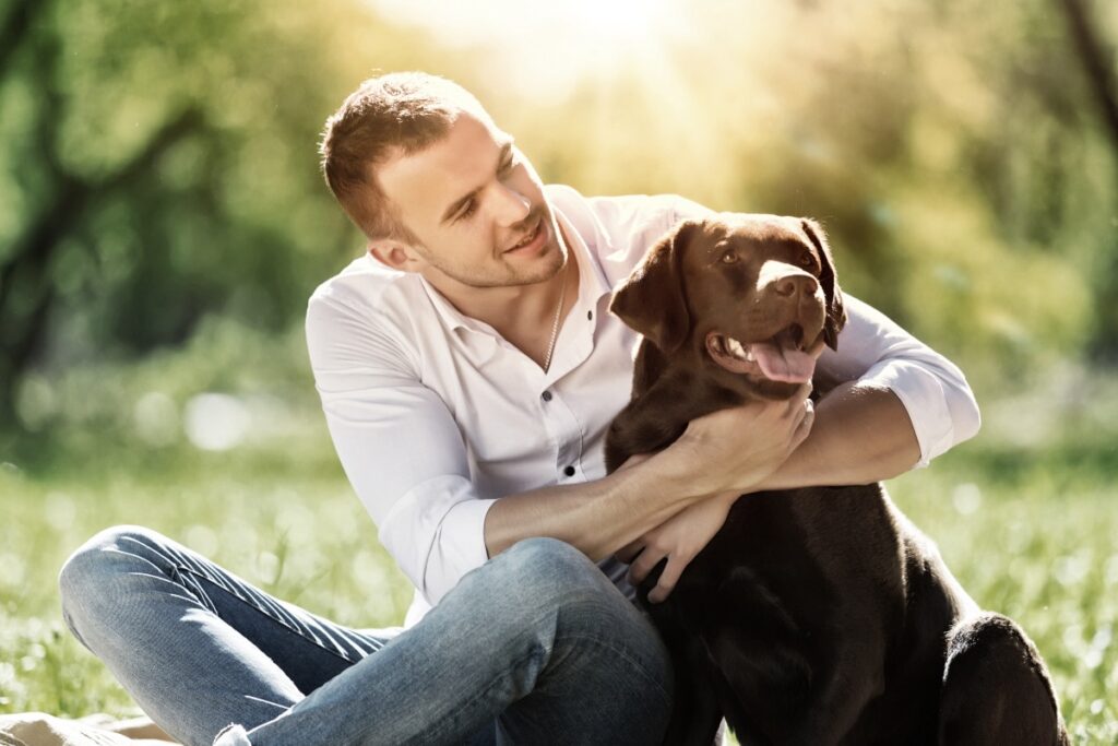 in der Hundeschule umarmt ein Mann seinen braunen Labrador im Einzeltraining